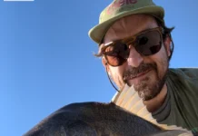 915 | How a Music Producer Built a Fly Fishing Podcast from Scratch with Pablo Signori Pablo Signori holding a large fish while fly fishing near a coastal city