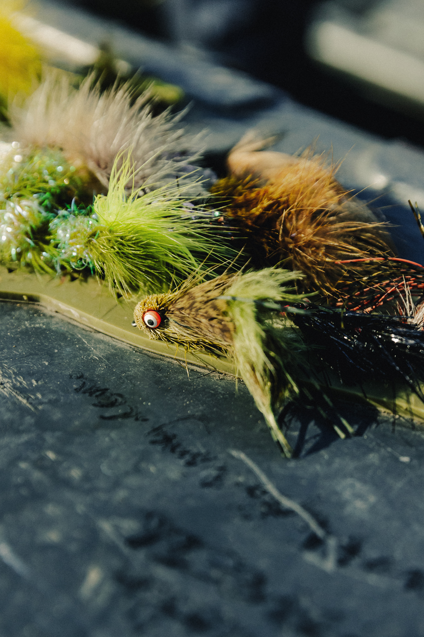 Close-up image of colorful topwater fly patterns, including Boogle Bugs and Mr. Wiggle Legs, used for smallmouth bass fishing.