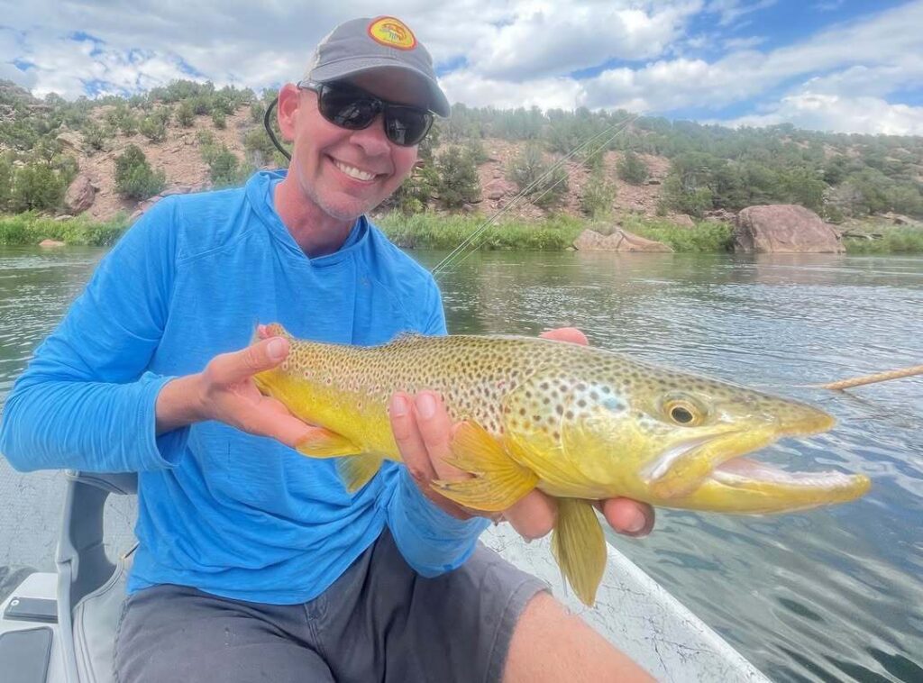 Gary Davis holding a brown trout while choosing the right fly rod for New Mexico river fishing