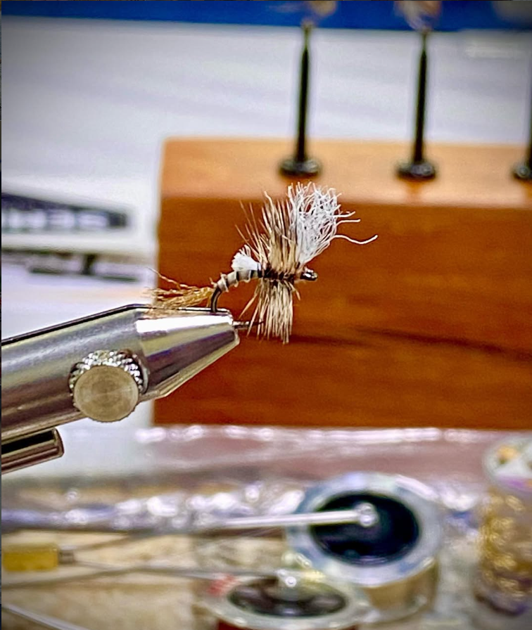 Close-up of a Quigley-style dry fly in a vise showing hackle stacker style wing post and emerger body used to imitate mayfly emergence for trout.