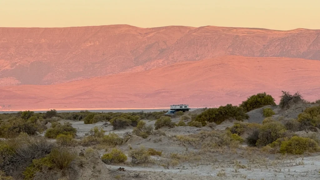 Our truck camper in distance with desert terrain at sunset