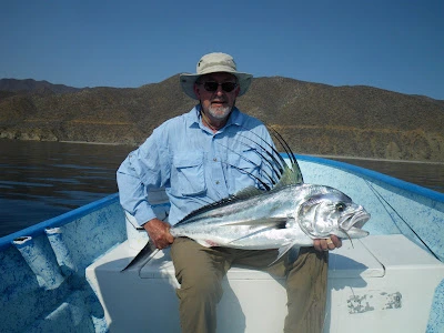 Larry Kenney holding a large fish on a boat during a fly fishing trip
