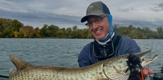 Rick Kustich holding a musky caught on a fly with a large streamer in its mouth