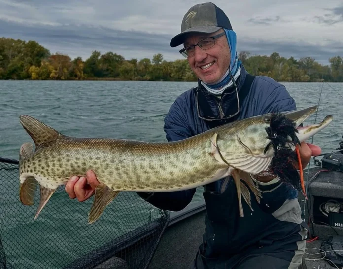 Rick Kustich holding a musky caught on a fly with a large streamer in its mouth