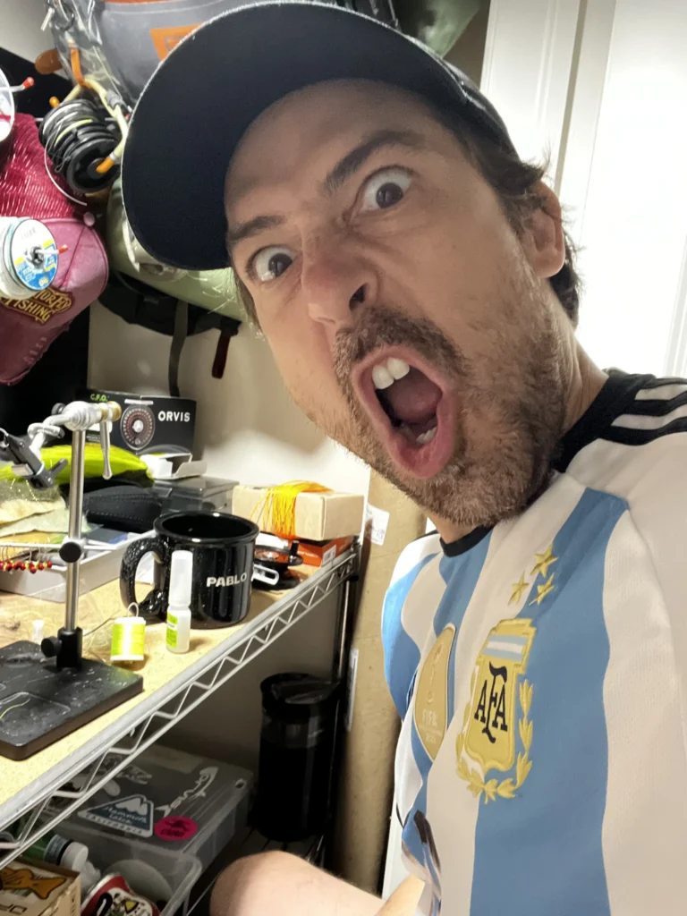 Pablo Signori at a fly tying desk making a funny expression while learning fly fishing and tying flies