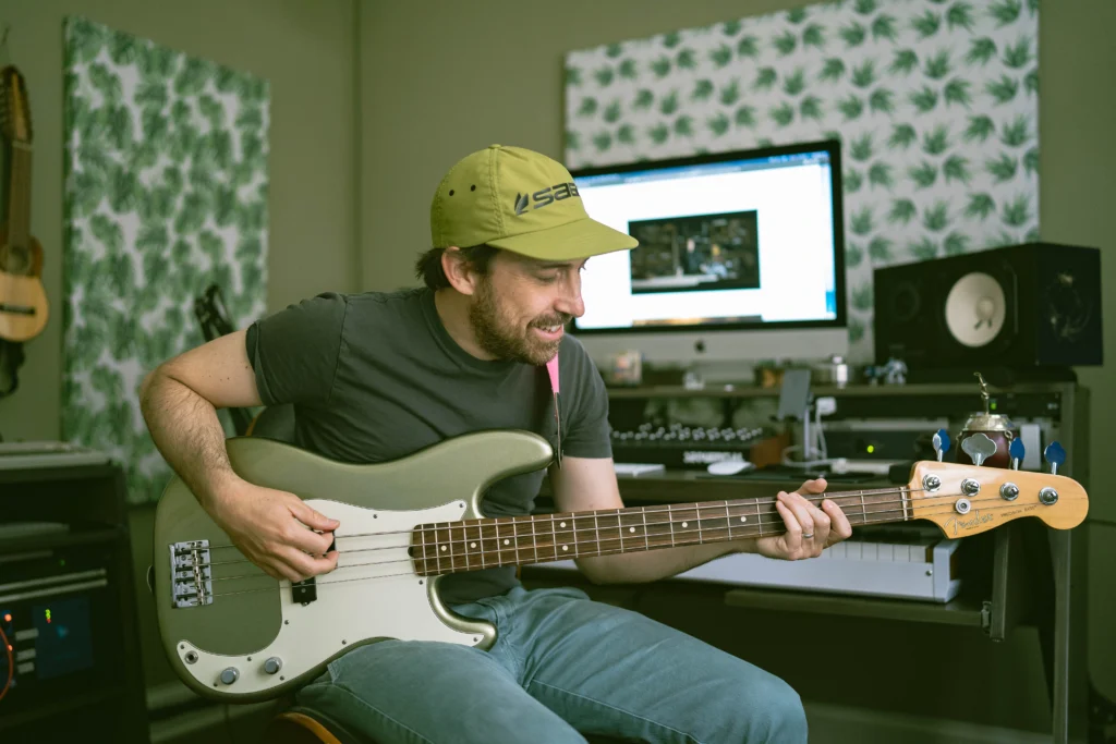 Pablo Signori playing bass guitar in his home studio as a music producer before transitioning into fly fishing