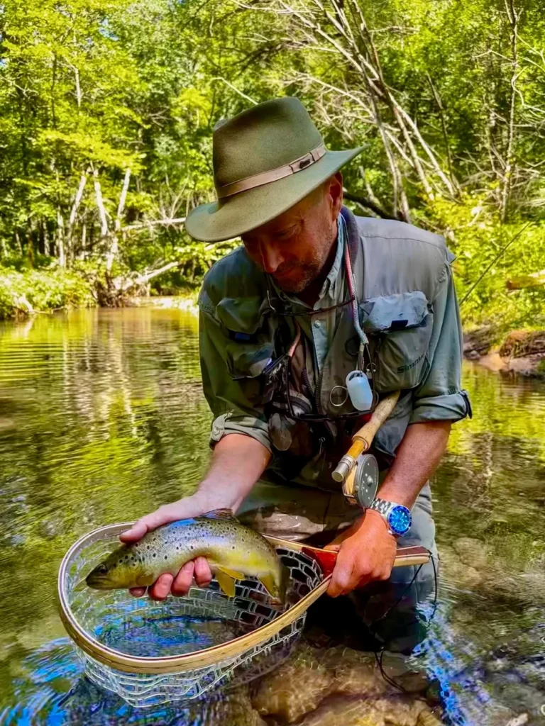 angler holding large brown trout in small driftless stream net