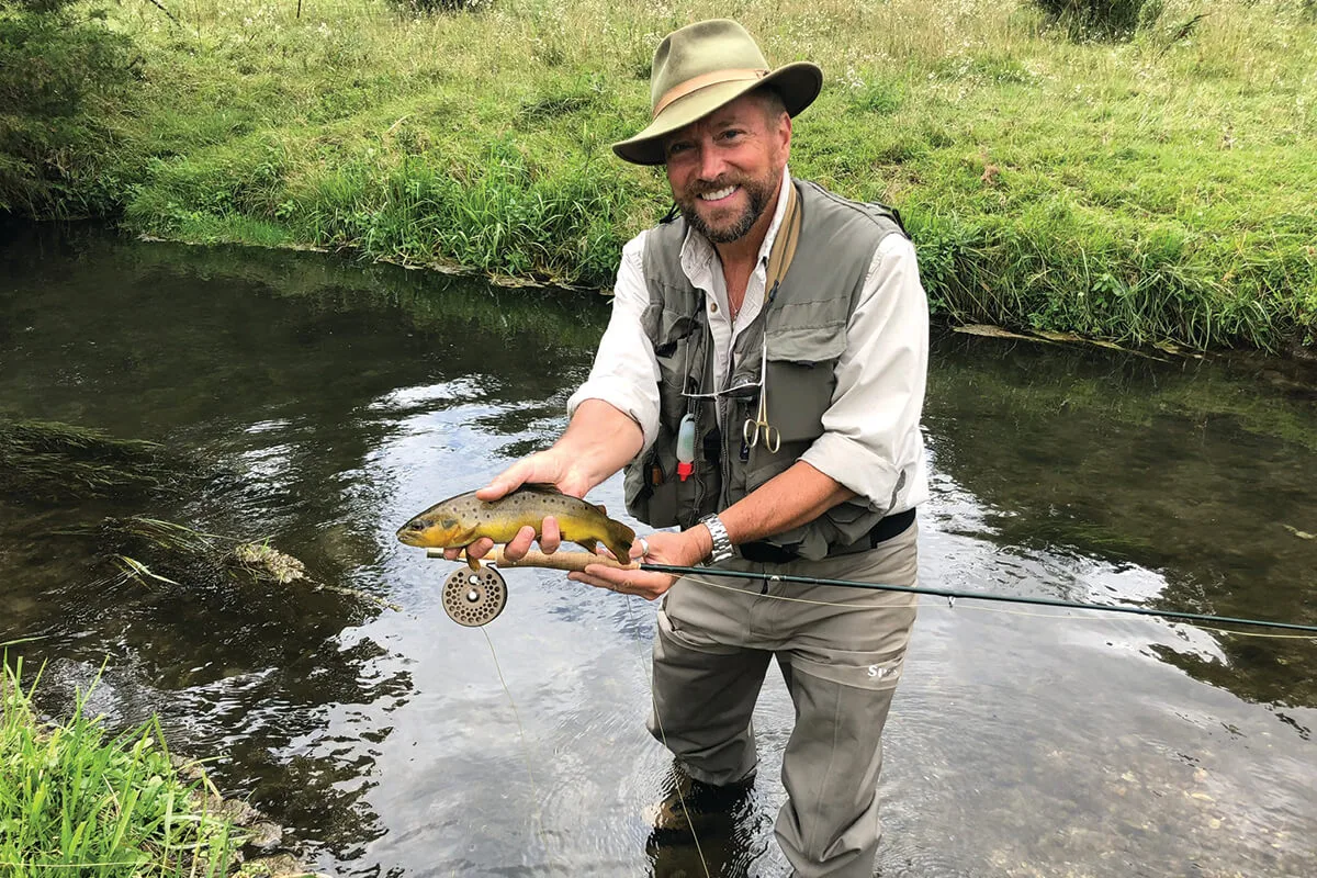 Angler holding a brown trout in a small Driftless spring creek