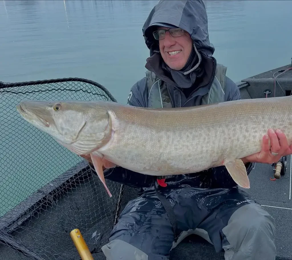 Rick Kustich holding a large musky caught on the fly from a boat